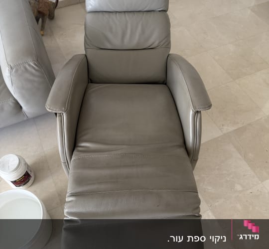 כורסה אפורה עם דלי ומיכל ניקוי על הרצפה